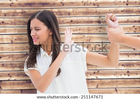 Fearful brunette being grabbed by the hand against wooden planks background