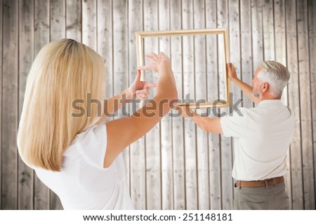 Couple hanging a frame together against wooden planks background