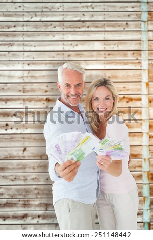 Happy couple flashing their cash against faded pine wooden planks