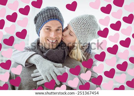Cute couple in warm clothing hugging man smiling at camera against valentines day pattern
