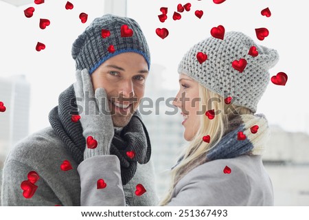 Cute couple in warm clothing hugging against valentines heart design