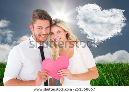 Attractive young couple holding pink heart against cloud heart