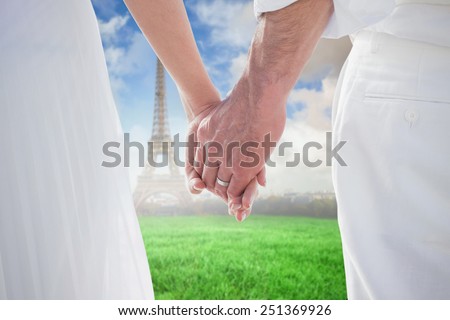 Bride and groom holding hands close up against eiffel tower