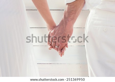 Bride and groom holding hands close up against painted blue wooden planks