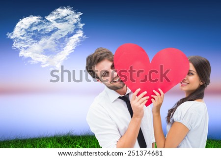 Couple smiling at camera holding a heart against cloud heart