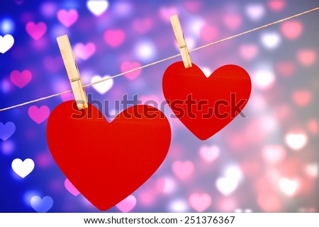 Hearts hanging on a line against valentines heart pattern
