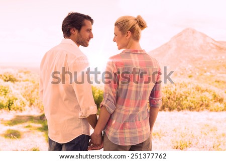 Cute couple standing hand in hand smiling at each other on a sunny day