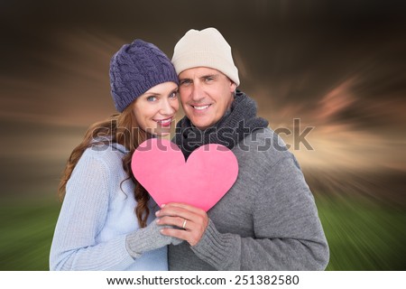 Happy couple in warm clothing holding heart against stormy sky over city