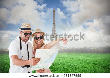 Happy tourist couple using map and pointing against eiffel tower