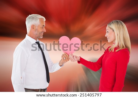 Handsome man getting a heart card form wife against large rock overlooking red sky