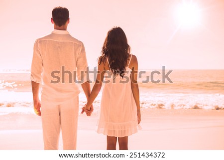 Attractive couple holding hands and watching the ocean at the beach