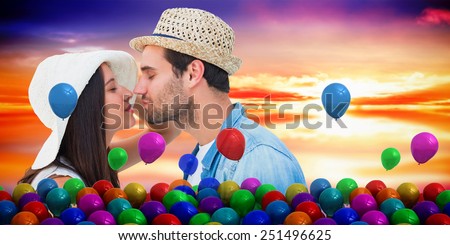 Happy hipster couple about to kiss against purple sky with orange clouds