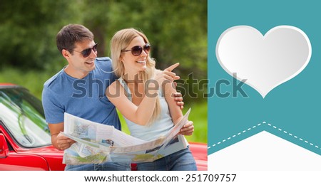 Cheerful young couple reading map against heart label