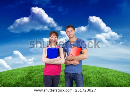 Two students both with notepads against green field under blue sky