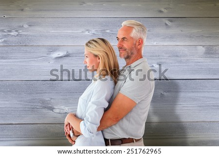 Happy couple smiling and embracing against bleached wooden planks background