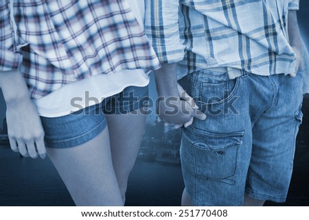 Couple in check shirts and denim holding hands against large moon over river city