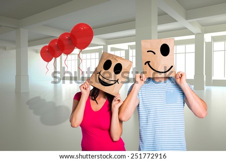 Young couple with bags over heads against white room with windows