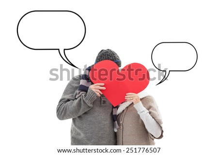 Happy mature couple in winter clothes holding red heart against speech bubble