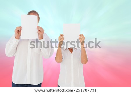 Couple holding paper over their faces against blue and pink light spot design