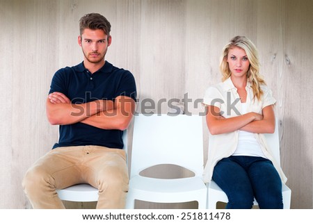 Young couple sitting in chairs not talking during argument against wooden planks