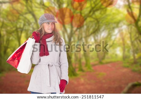 Happy blonde in winter clothes with bags against peaceful autumn scene in forest