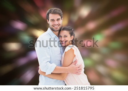 Attractive young couple hugging and smiling at camera against valentines heart design