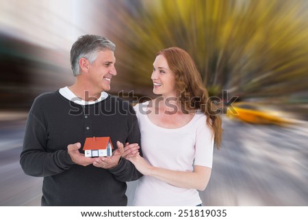 Casual couple holding small house against blurry new york street