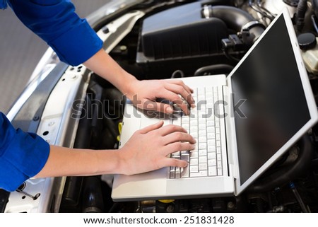 Mechanic using laptop on car at the repair garage