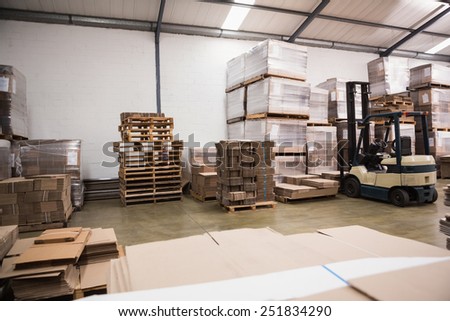 Forklift amid rows of boxes in a large warehouse