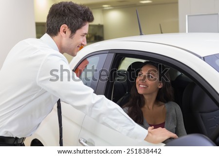 Salesperson speaking with happy client at new car showroom