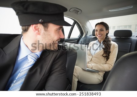 Young businesswoman being chauffeured while working in the car