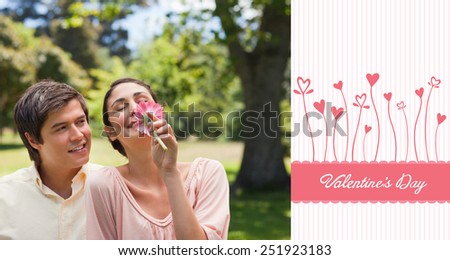 Man watching his friend while she is smelling a flower against valentines graphic