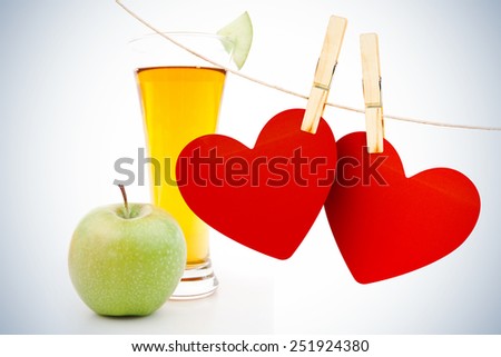 Hearts hanging on line against apple near a glass of apple juice