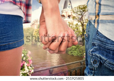 Couple in check shirts and denim holding hands against canal in amsterdam