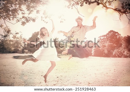 Cute couple jumping in the park together on a sunny day