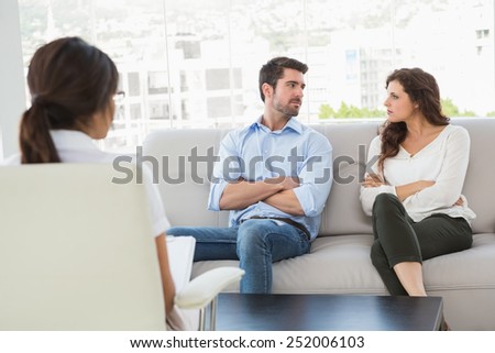 Unsmiling couple talking with their therapist in the office