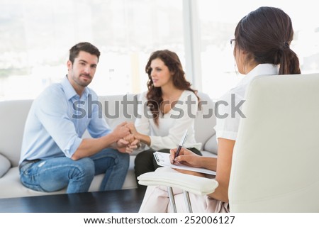 Reconciled couple smiling at each other in the therapist office