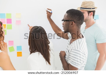 Rear view of coworkers writing on sticky notes in the office
