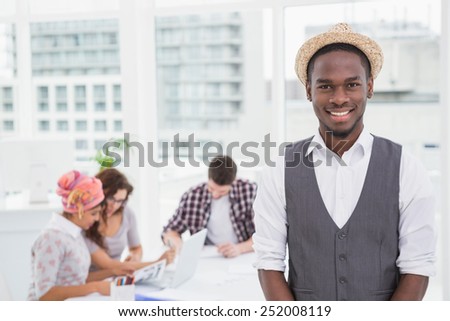 Casual businessman smiling at camera with colleagues behind him