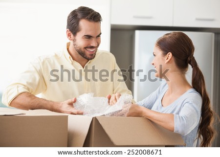 Young couple unpacking boxes in kitchen in their new home