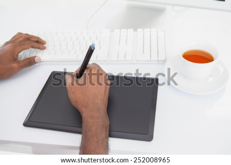 Designer using computer and digitizer with tea in the office