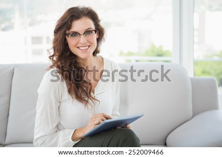 Smiling businesswoman using tablet on couch in the office