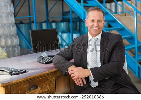 Portrait of smiling warehouse manager with computer at warehouse