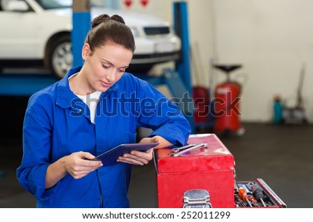 Mechanic using her tablet pc at the repair garage