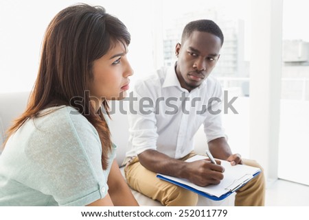 Serious therapist listening to his talking upset patient at therapy session