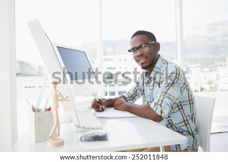 Smiling casual businessman writing on paper in the office