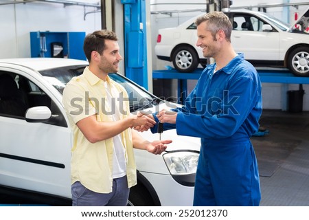 Customer shaking hands with mechanic taking keys at the repair garage