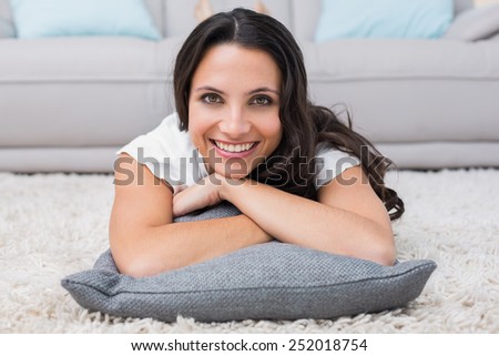 Pretty brunette lying on the rug at home in the living room