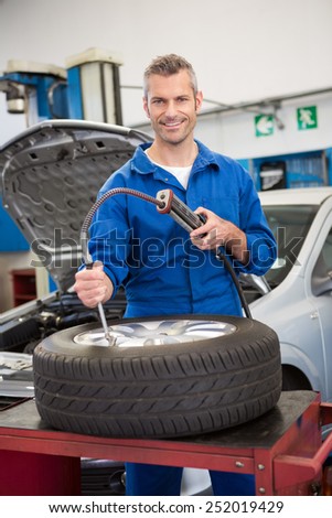 Smiling mechanic inflating the tire at the repair garage