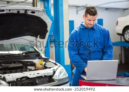 Concentrated mechanic using his laptop at the repair garage